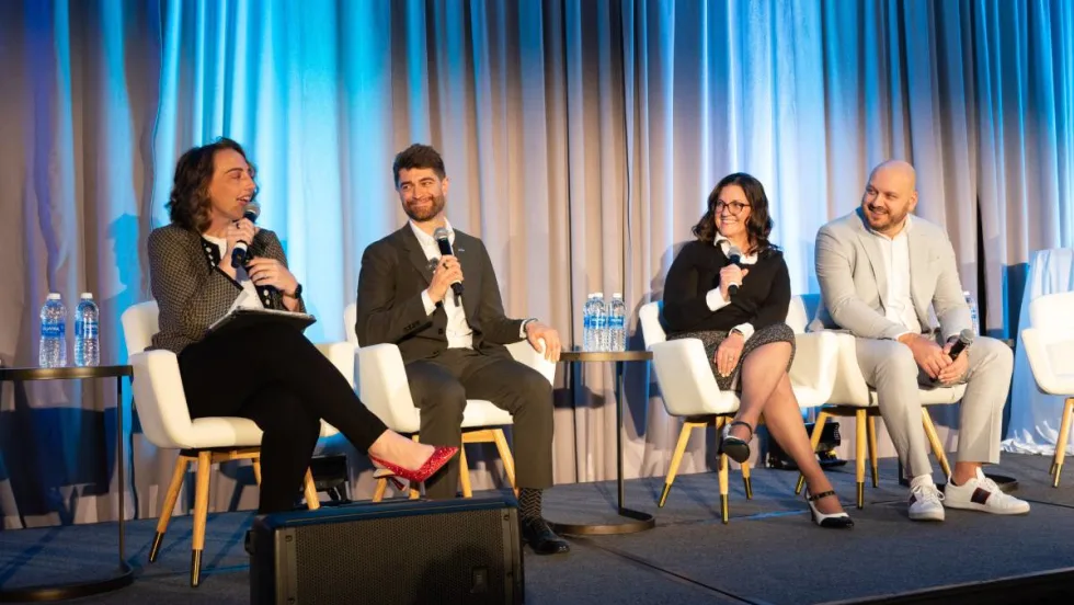 Panelists on stage in front of curtain during conference.