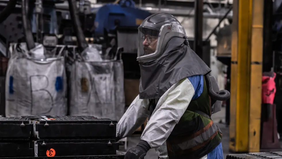Technician handling electric vehicle battery components in a recycling facility as Cox Automotive expands EV battery processing and material recovery operations.