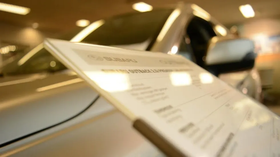 Sales board in front of a car inside a dealership showroom floor.