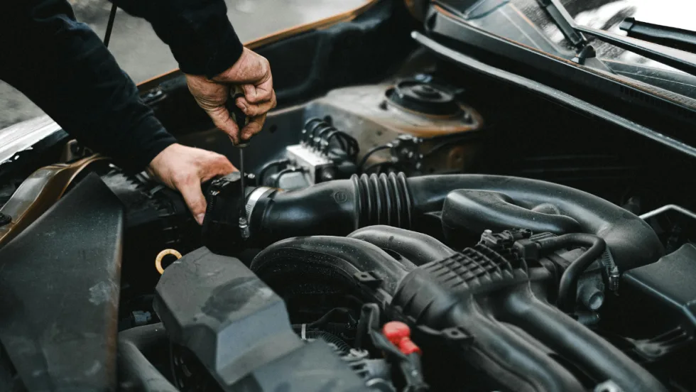 The hands of an auto mechanic checking the engine of a car.