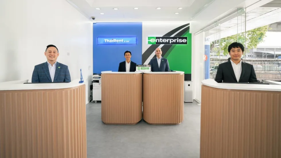 Representatives of Thai Rent-A-Car stand at airport service counters.