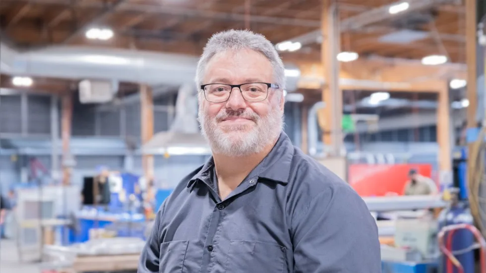 A professional portrait of Bruce Birdsell in a workshop/warehouse.