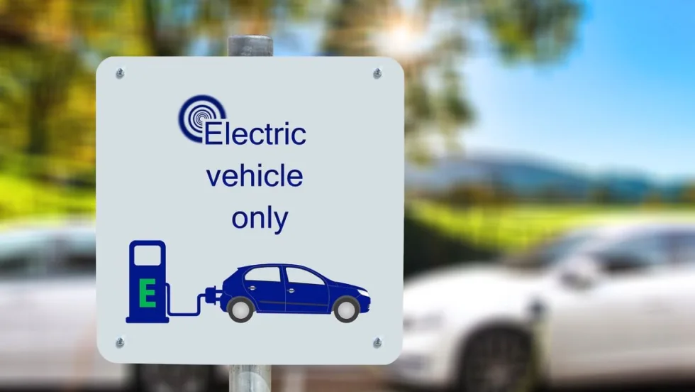 Image of a sign that says "Electric Vehicle Only" in front of charging vehicles.