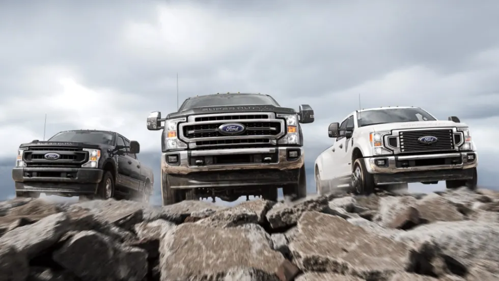 Various 2021-2022 Ford Super Duty driving on rocks towards the camera.