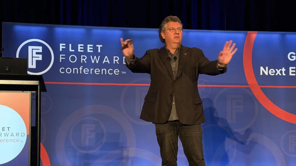 Speaker Bill Sims on the FFC stage with both hands up, emphasizing a point during his safety keynote address.