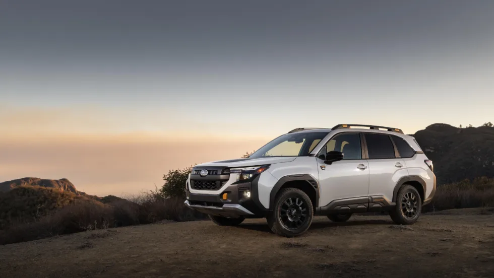 The Subaru Forester Wilderness drives in the desert with a sunset falling behind it. 