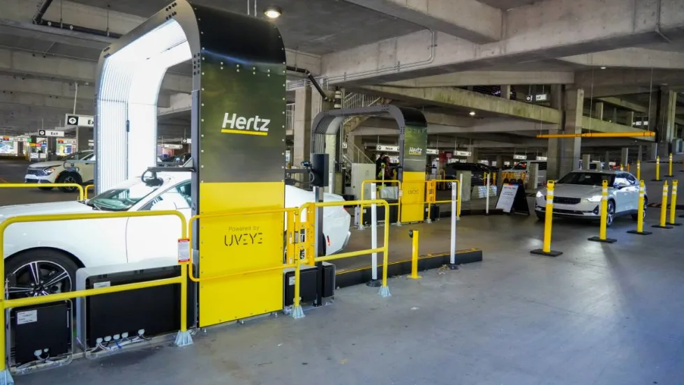 A vehicle inspection arch-style imaging structure that takes photos of rental cars returning to an airport parking deck.