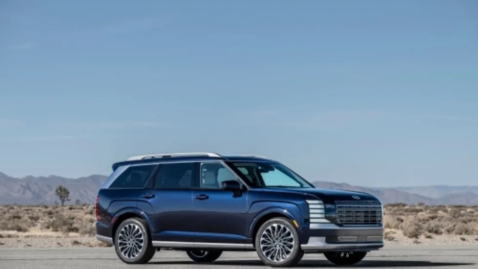 A dark blue full-size SUV parked on a desert road, with sleek modern styling, large alloy wheels, and a chrome-accented grille, set against a backdrop of dry desert landscape.