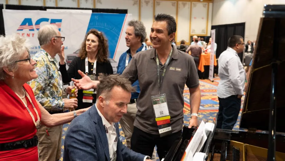 Attendee playing piano on exhibit floor and entertaining guests.