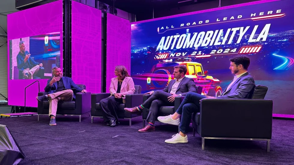Photo of three panelists on stage during a seminar at LA Auto Show. 