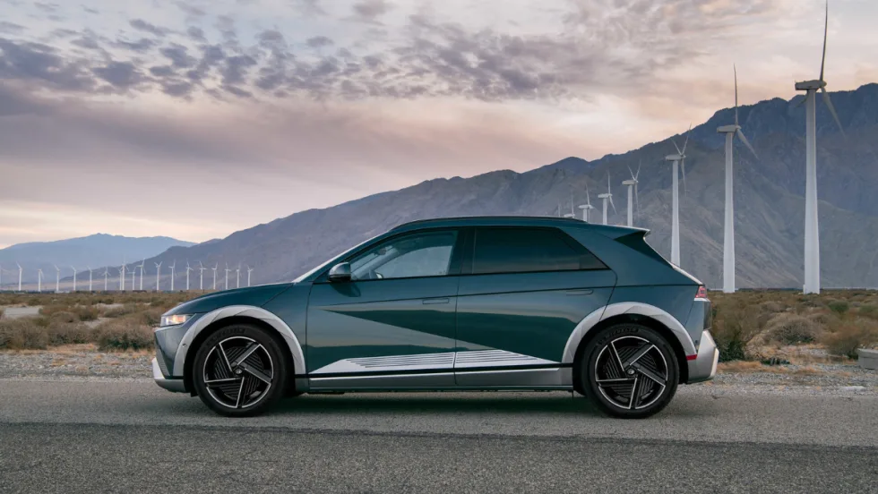 Hyundai IONIQ 5 electric SUV parked near wind turbines, named Best Compact Electric SUV, highlighting fast charging, modern design, and efficiency.