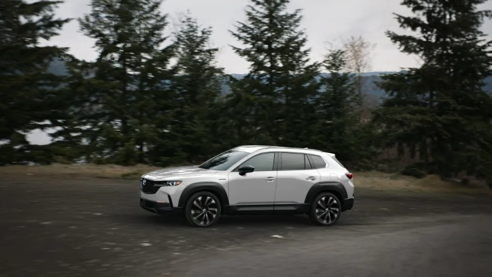 A silver Mazda SUV being driven on a mountain road. 