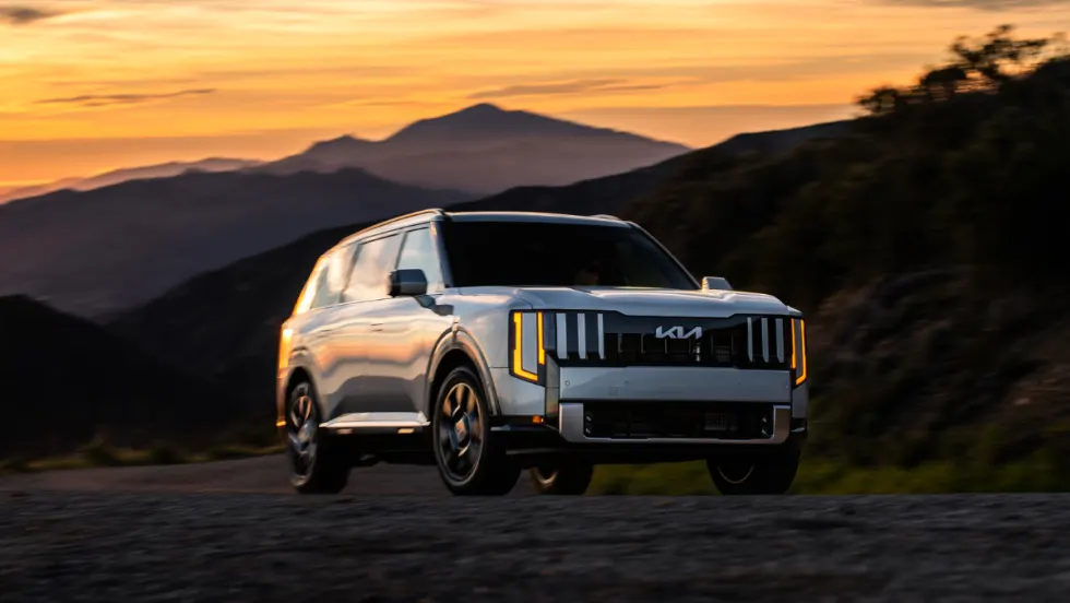 Kia Telluride hybrid SUV driving on a mountain road at sunset, highlighting award-winning electrified models recognized by U.S. News for performance, efficiency, and value.