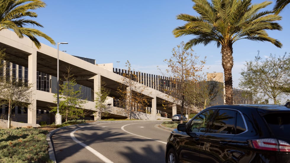 A close up of a roadway leading ot the entrance of the multi-deck LAX Rental Car Center.