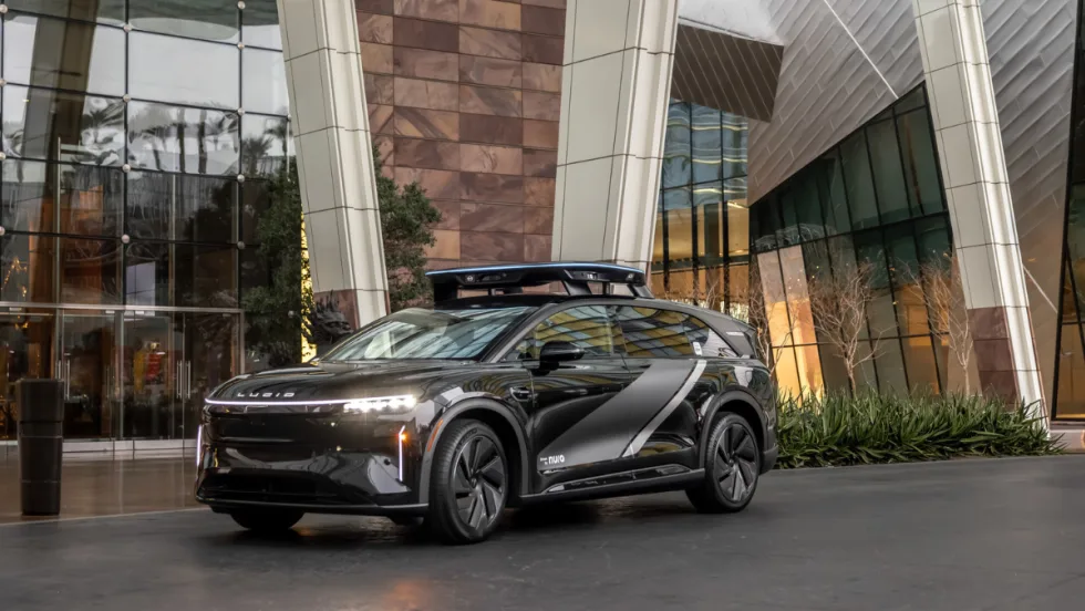 Lucid electric vehicle equipped with rooftop sensors parked outside a modern building, representing expanded partnership with Uber for future robotaxi deployment.
