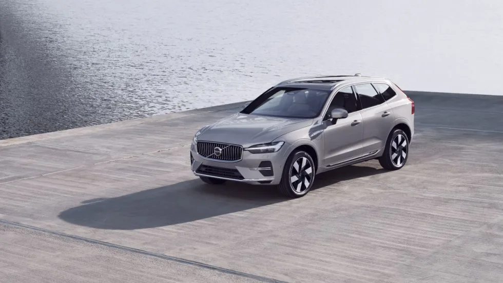 A silver SUV sits on a gray concrete surface with water in the background.