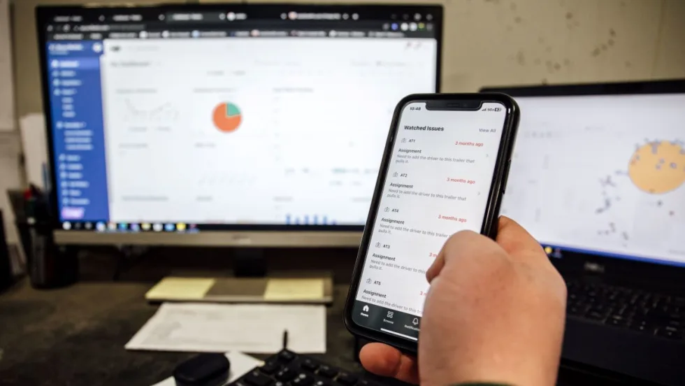 A hand holding a cell phone with fleet information