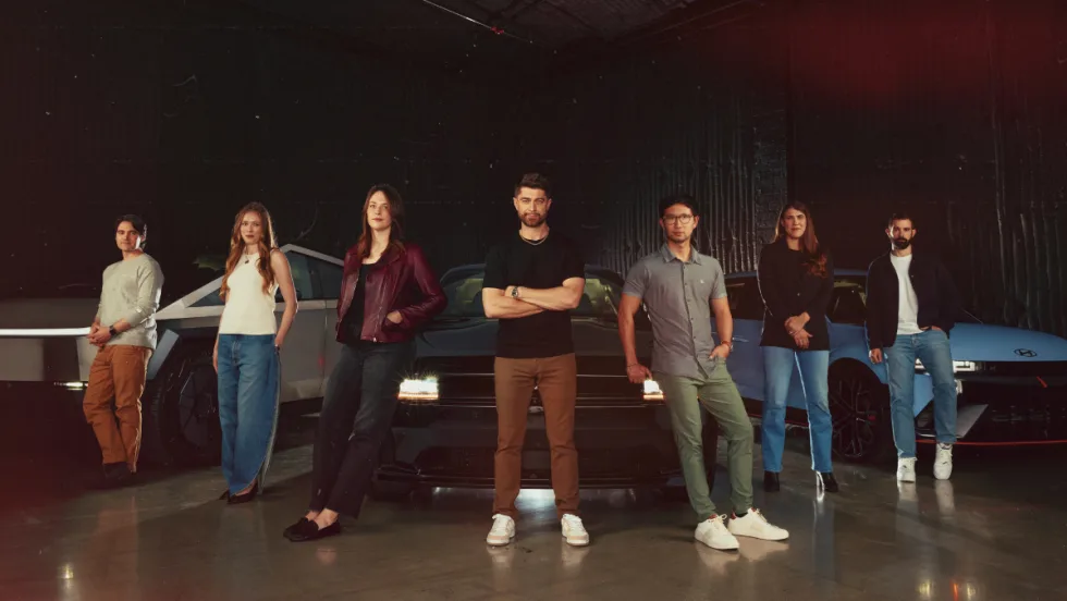 Plug's executive team standing in a V-formation in front of several Tesla electric vehicles.