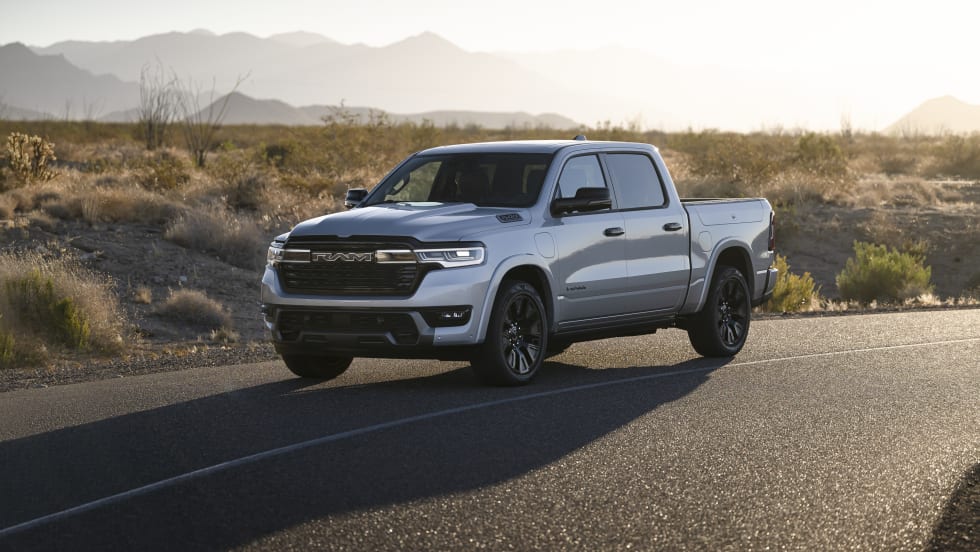 “Silver Ram pickup truck parked on a desert highway with mountains in the background at sunset.”