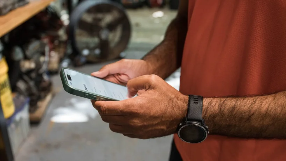 Person holds phone in both hands to read safety analytics for fleets.