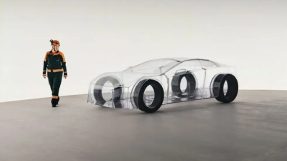 A Sandvik engineer stands beside the transparent eNimon installation, a full-scale model of an electric car made without any metals or minerals, symbolizing the importance of mining for EV production.