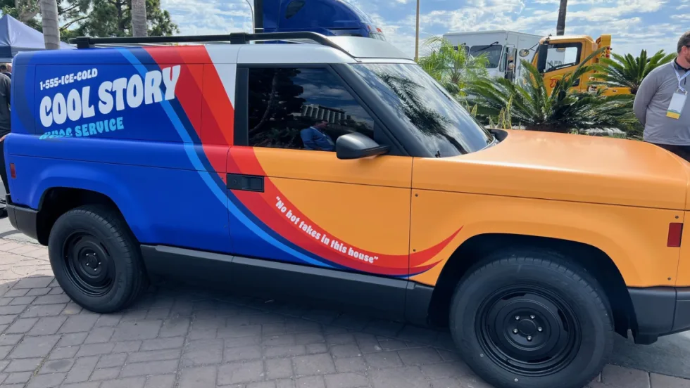 A side view of the yellow, blue, and red Slate Auto electric pick-up truck and SUV