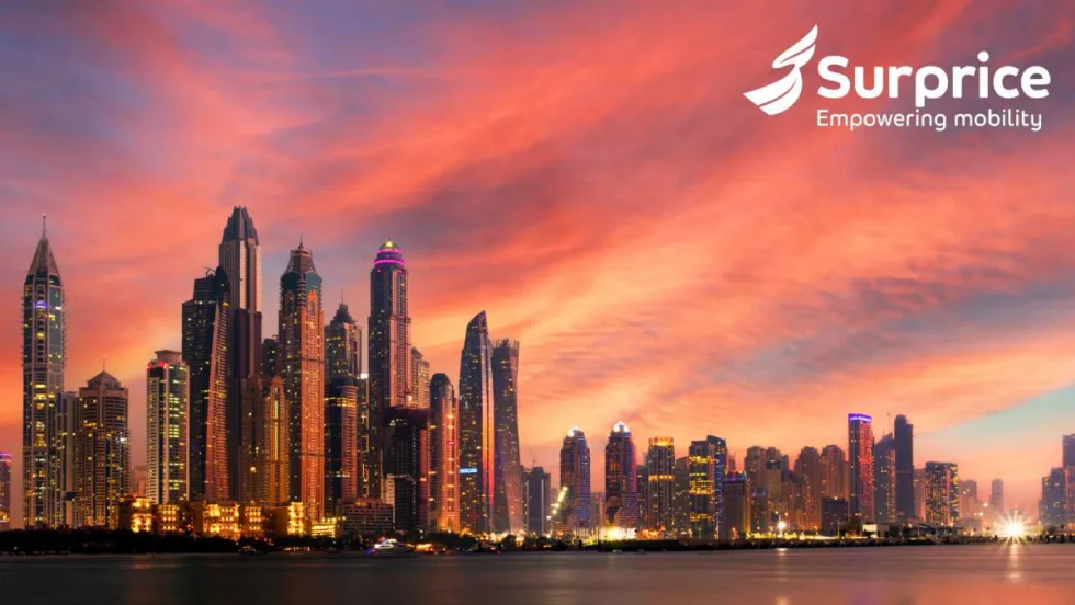 Glittering waterfront Dubai skyline against a reddish sunset sky.
