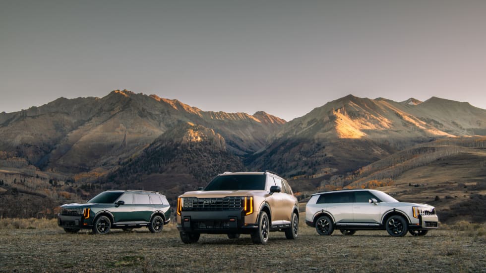 A 2027 Kia Telluride SUV sits on a mountain landscape with two others on each side. 