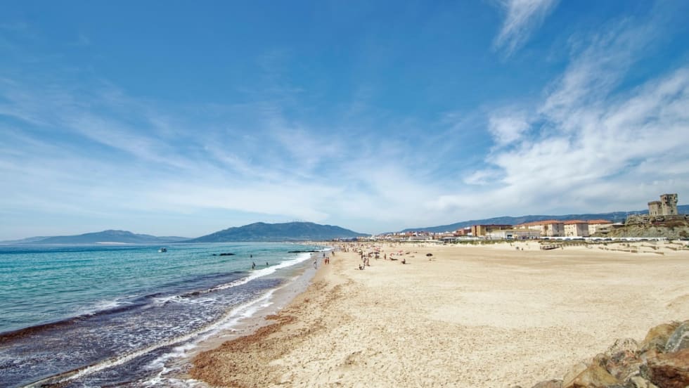 A wide Spanish beach is mostly empty.