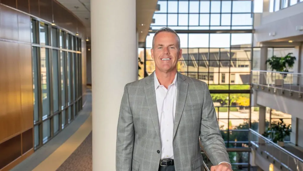 TSD's CEO posed in the atrium of a large modern office building.