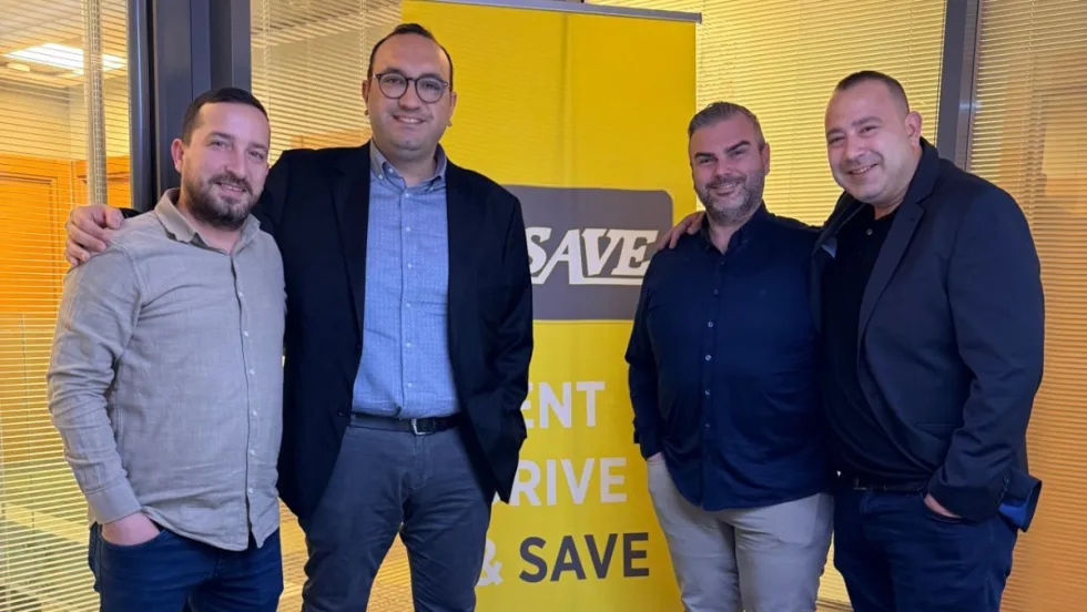 Four U-Save franchisees in front of a U-Save car rental banner.