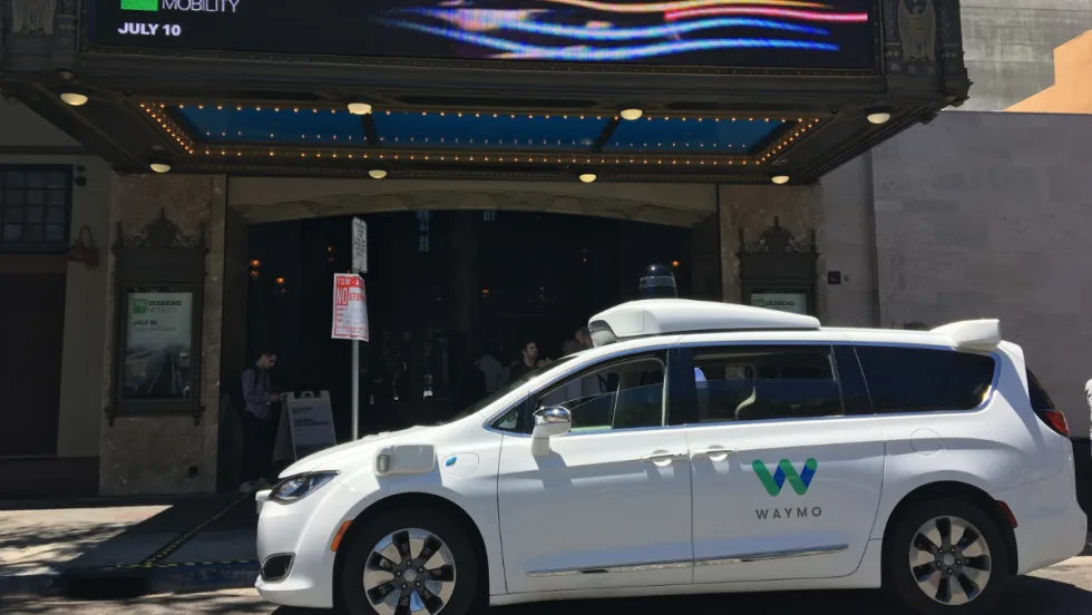 Waymo minivan in front of a theater.
