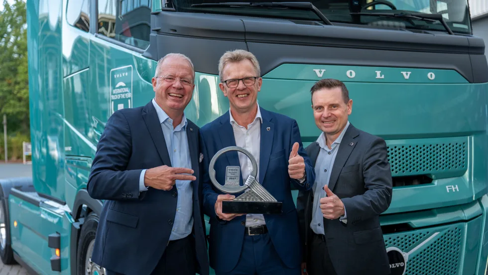 Three Volvo leaders stand in front of a turquoise Volva truck
