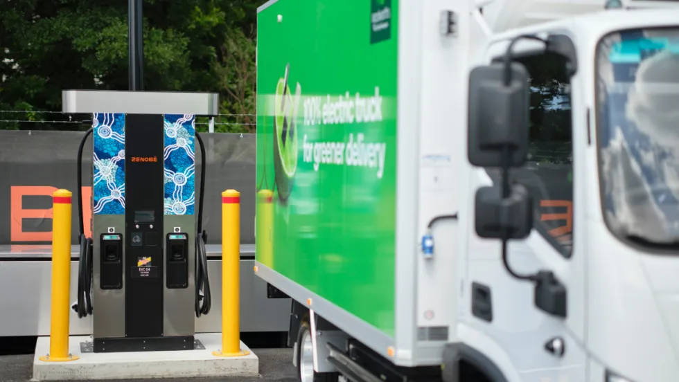 Electric delivery truck charging at a Zenobē station in a commercial lot, highlighting fleet electrification and growth of zero-emission truck infrastructure in the U.S.