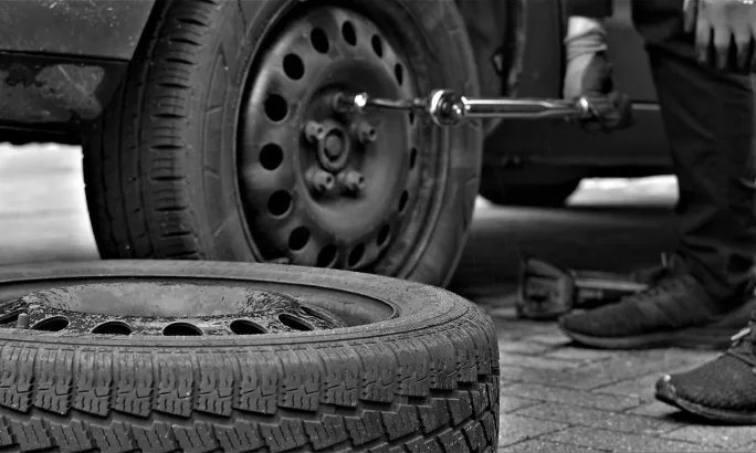 A truck with a flat tire, tire wrench, and car jack.