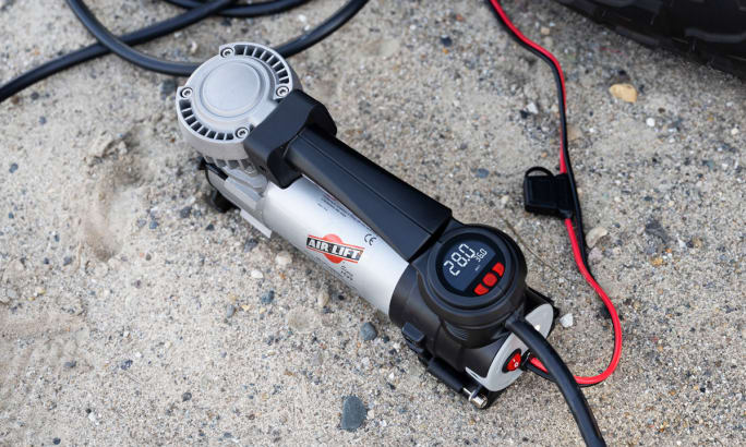 Air compressor in operation on ground next to a tire.