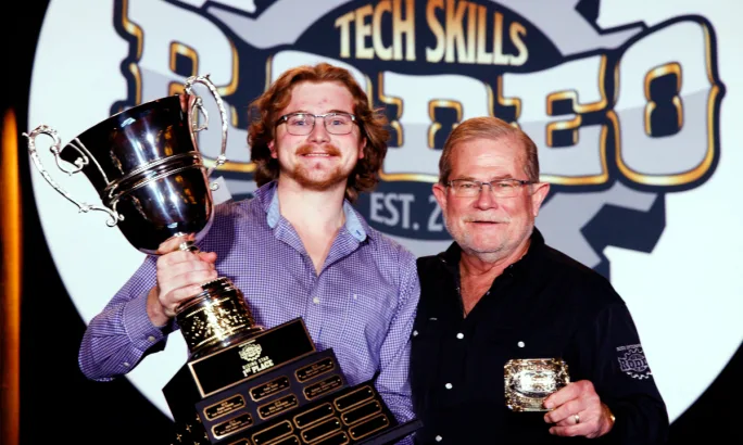 Young man receives trophy from older man.