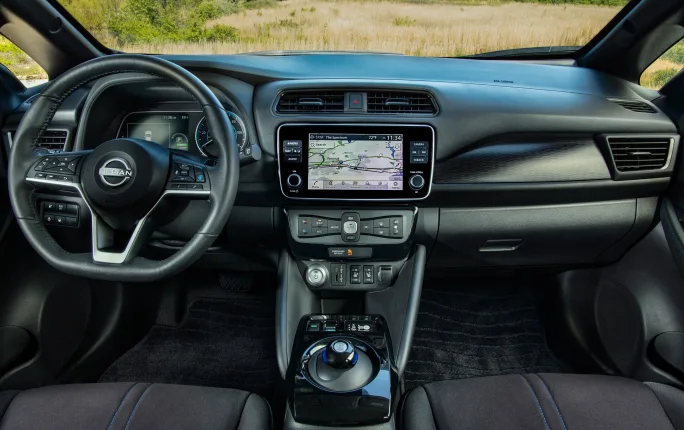 An interior vehicle photo shows the driver and passenger seats, with an infotainment center in the middle and the steering wheel on the left.