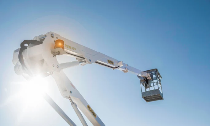bucket truck boom extended against a blue sky.