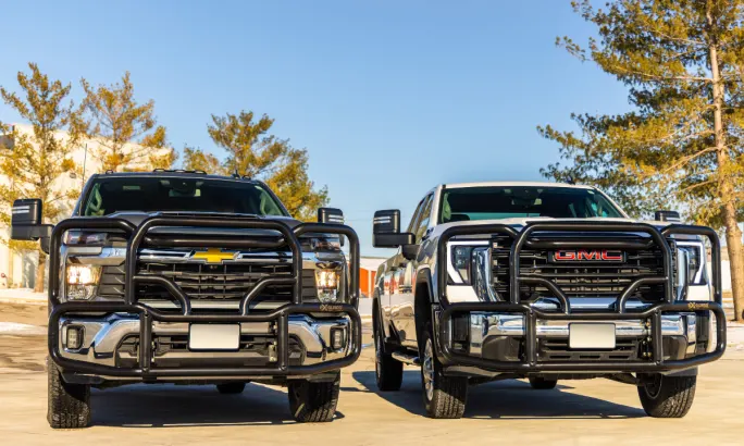 View shows front of a GM and a Chevrolet pickup equipped with black grille guards.