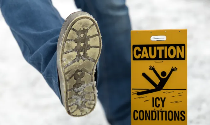 person slipping on ice with Caution: Icy conditions sign