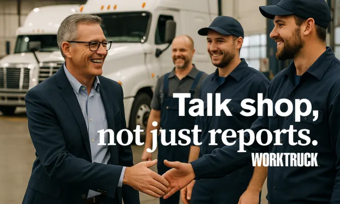 Fleet manager smiling and shaking hands with technicians in front of white trucks inside a maintenance facility.