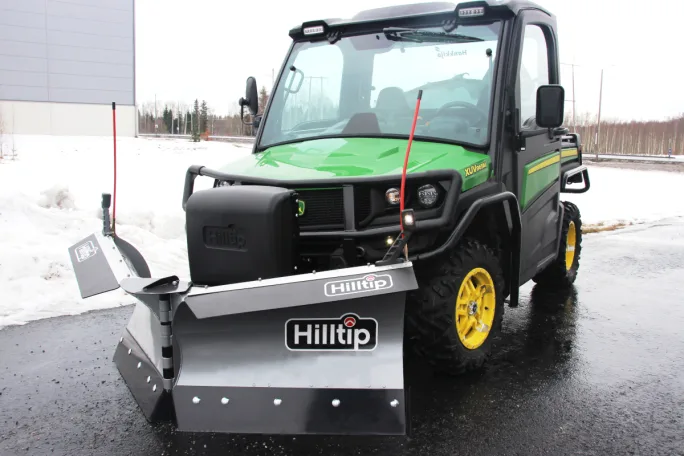 Snow plow attached to green and black UTV.