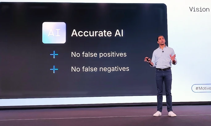 Man speaking on a stage in front of a screen that says Accurate AI.