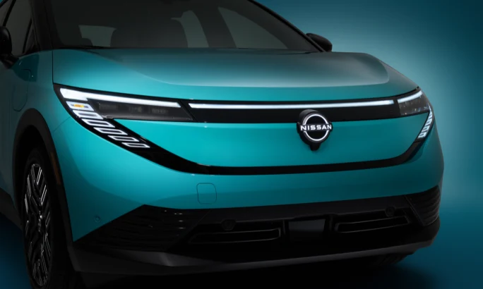 Close-up of the 2026 Nissan LEAF’s front fascia with illuminated Nissan badge and sleek headlights.
