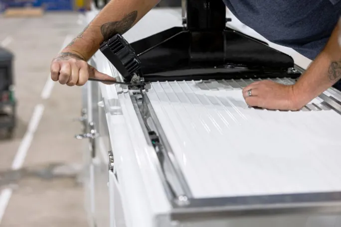 Installer works on a rail system that allows the installation of gear of the side packs of a mechanic truck.