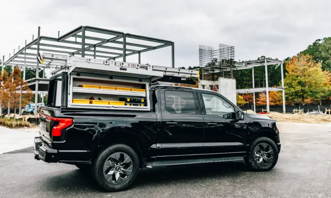 Side view of a pickup truck with a modular storage system parked at a construction site.