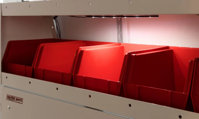 Red storage bins installed on van shelving.