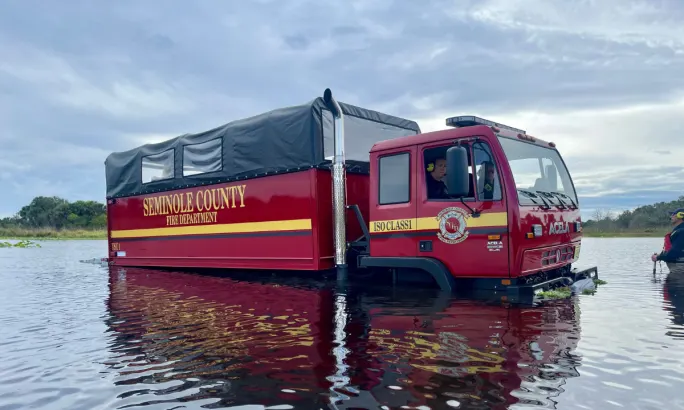 Red Seminole County Fire Department Acela rescue truck driving through deep floodwater during emergency response.