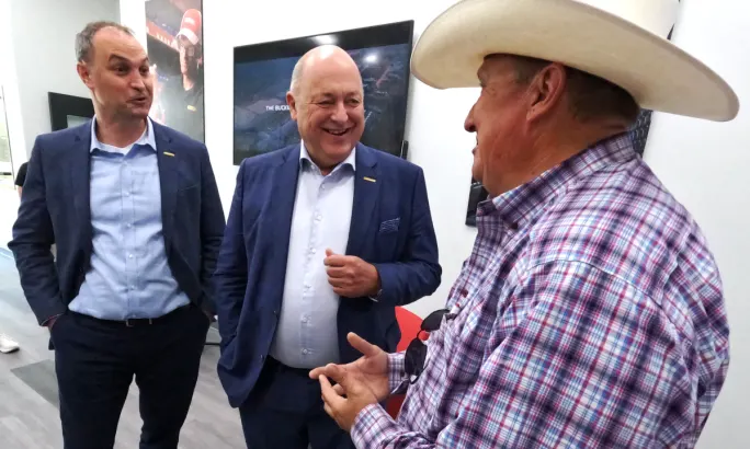 Three business men talk and smile.